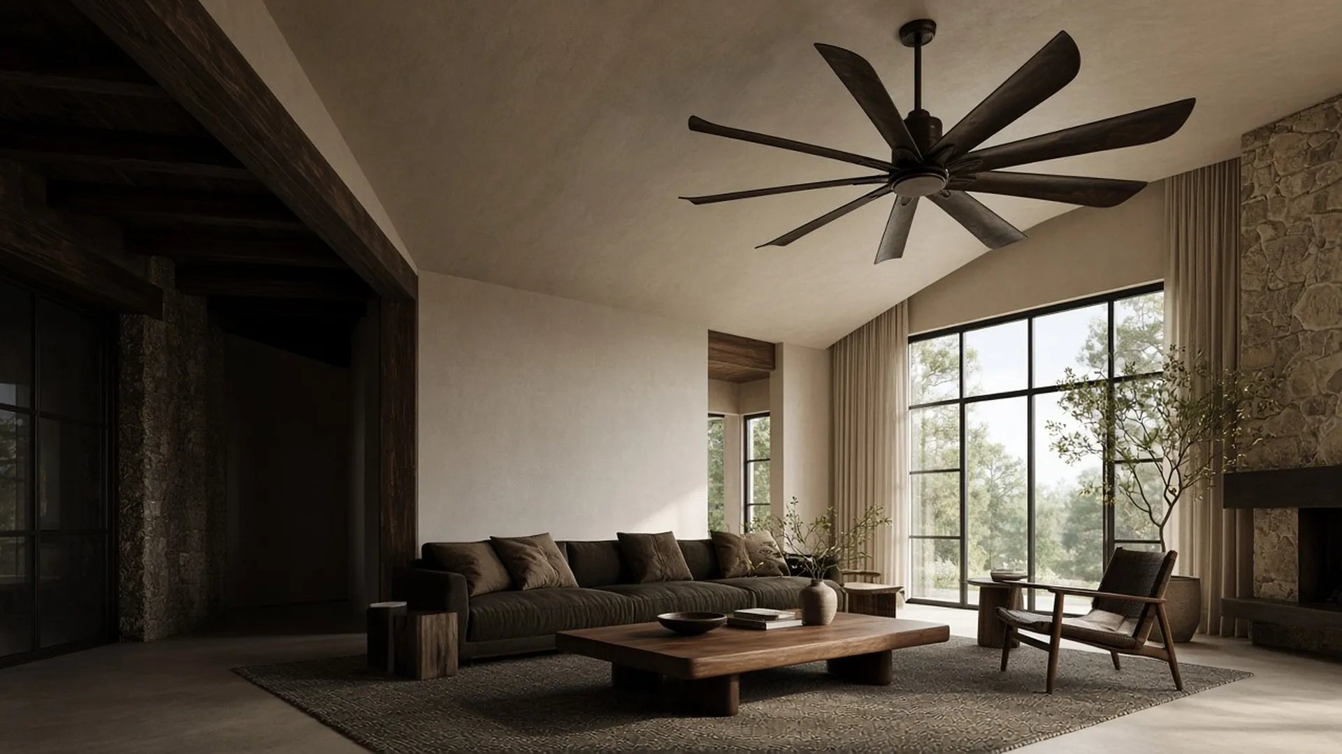 A wide great room with a large dark-bronze ceiling fan centered over a low walnut coffee table