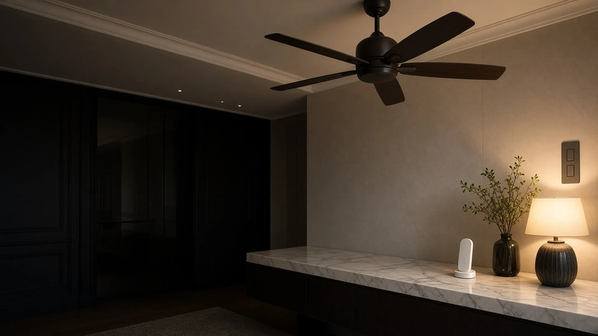 A minimalist wall plate fan control and a small unbranded remote on a marble console beneath a softly turning ceiling fan